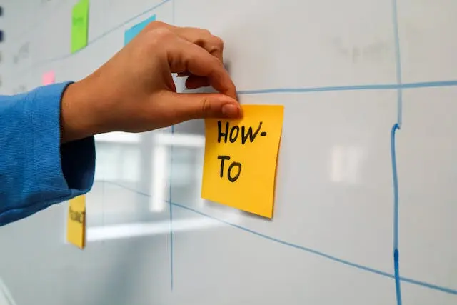 Persona poniendo post it en una pizarra para mejorar la inteligencia emocional y generar mejor experiencia de empleado.