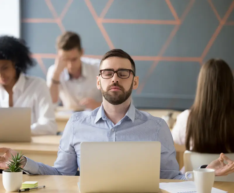 Equipo de oficina participando en una sesión de meditación y mindfulness en directo para mejorar el clima laboral.